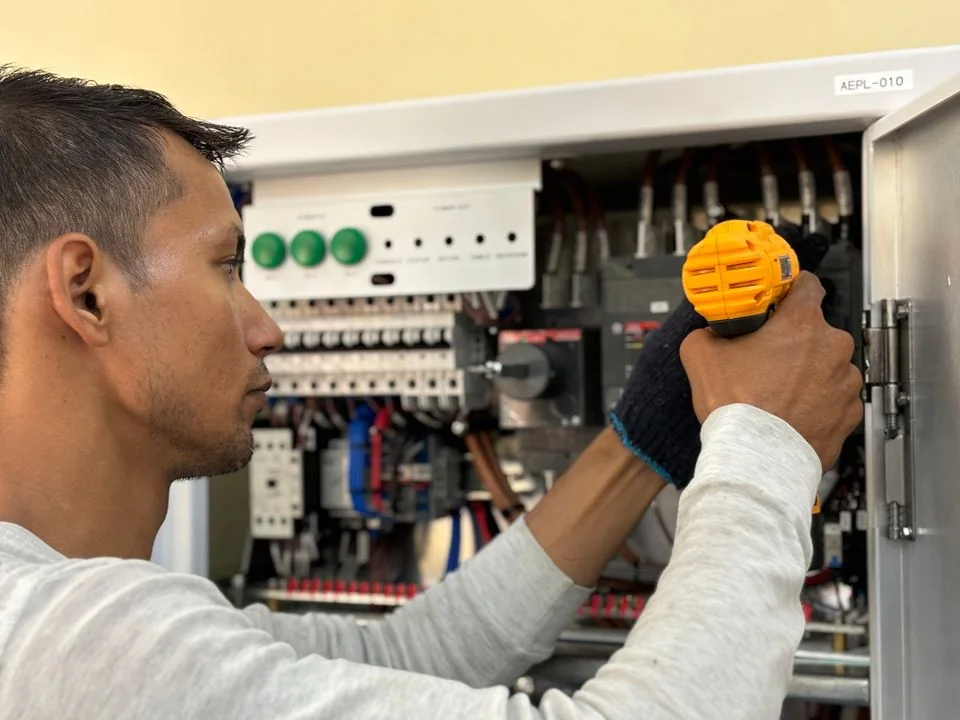 Electrician servicing an electrical control panel.