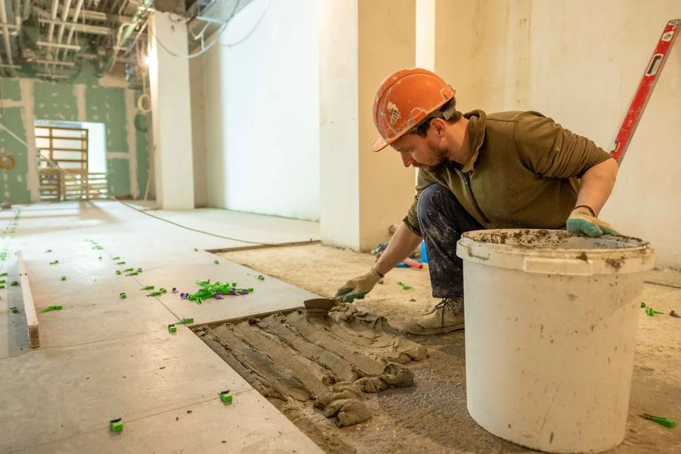 Flooring installer setting tiles during an interior renovation.