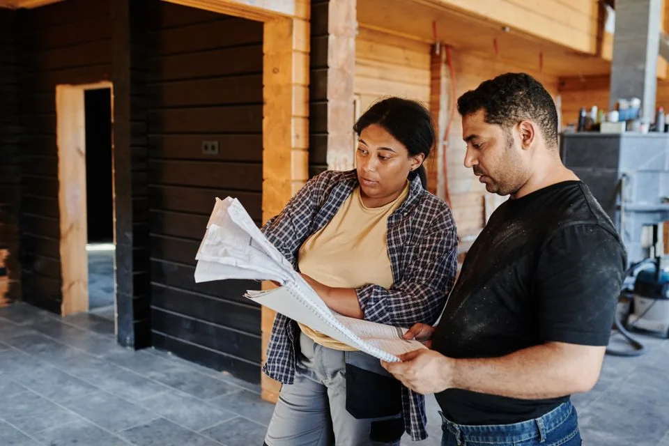 Construction team reviewing plans inside a framed building.