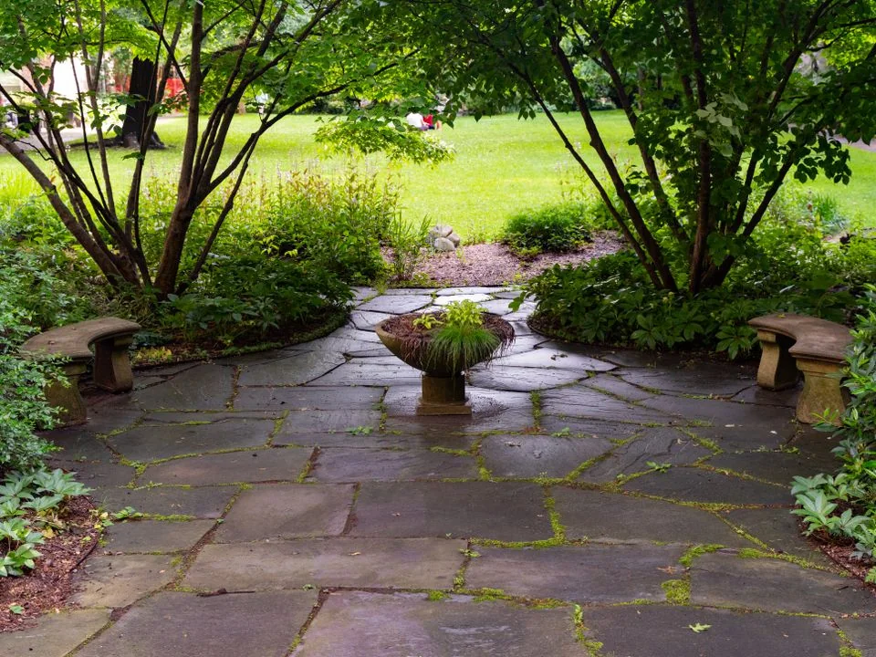 Stone garden patio surrounded by leafy planting.