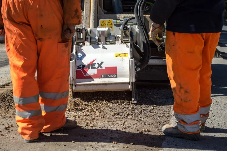 Construction crew operating an asphalt paving machine.
