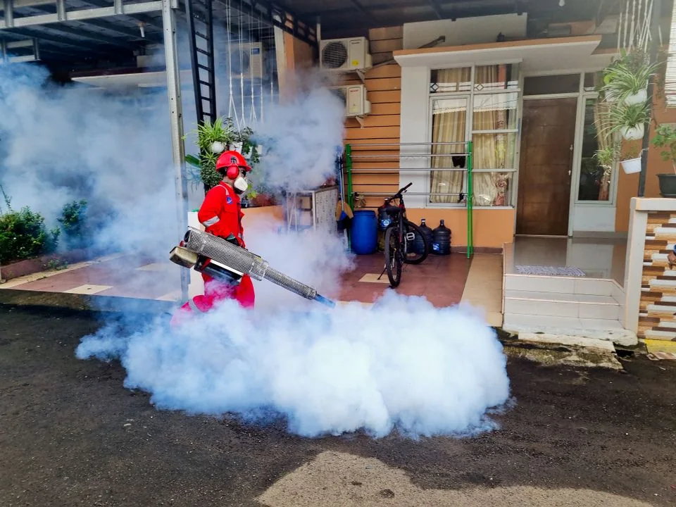 Pest control worker treating an outdoor residential area.