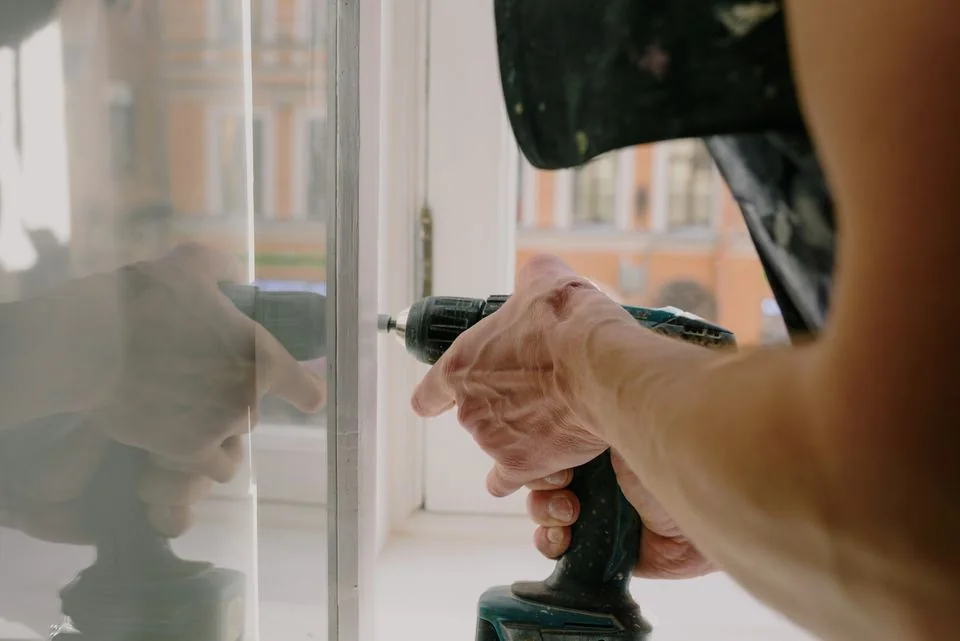Installer fastening hardware on a white window frame.
